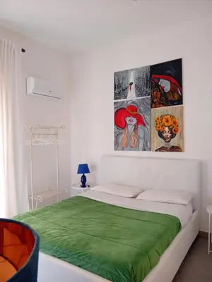 a white bedroom with a bed with a green blanket at BBX Palermo 2 in Palermo