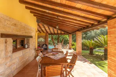 a patio with a table and chairs under a wooden pergola at Villa Cecilia in Cinisi