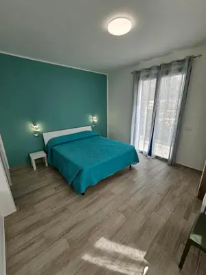 a bedroom with a blue bed and a wooden floor at Un Posto Al Sole in San Vito lo Capo