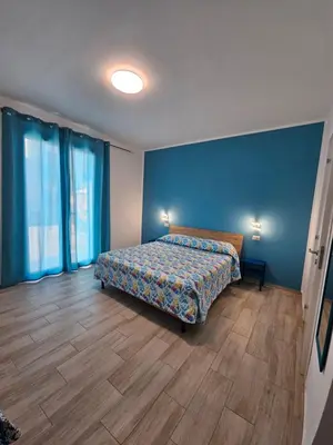 a bedroom with a bed and a blue wall at Un Posto Al Sole in San Vito lo Capo