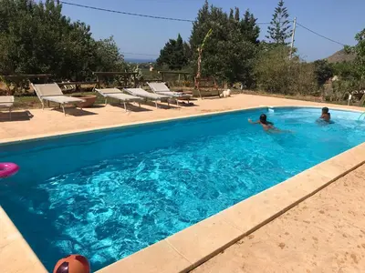 two people swimming in a blue swimming pool at VILLa CON PISCINA SCOPELLO in Castellammare del Golfo