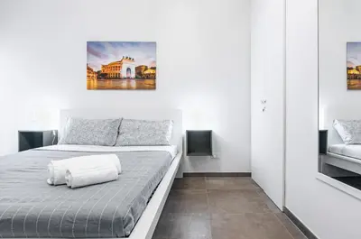a white bedroom with a bed and a painting on the wall at GuestHost - Palazzo dei Normanni & Ballarò Roomy Modern Apt x9 in Palermo
