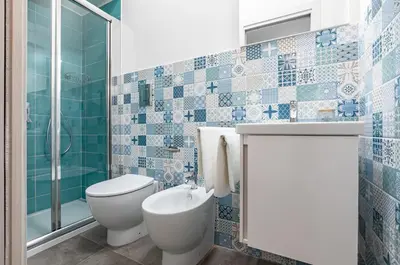 a blue tiled bathroom with a toilet and a shower at GuestHost - Palazzo dei Normanni & Ballarò Roomy Modern Apt x9 in Palermo