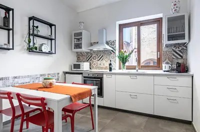 a kitchen with white cabinets and a table with red chairs at GuestHost - Palazzo dei Normanni & Ballarò Roomy Modern Apt x9 in Palermo