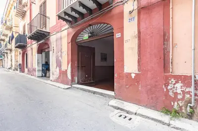 a red building with an open door on a street at GuestHost - Palazzo dei Normanni & Ballarò Roomy Modern Apt x9 in Palermo