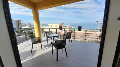 a balcony with chairs and a table and a view of the ocean at Casa L'ORIZZONTE in Balestrate