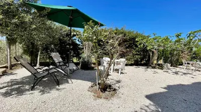 a group of chairs and an umbrella and trees at Residence Cavalluccio Marino in Alcamo Marina