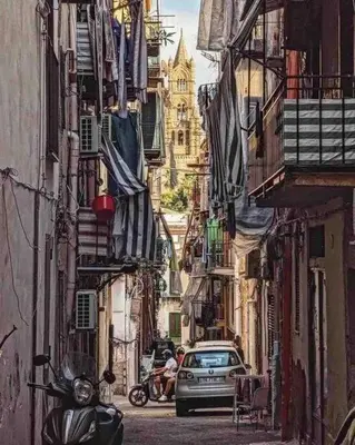 a car driving down a narrow street with buildings at Cathedral cozy apartment in Palermo