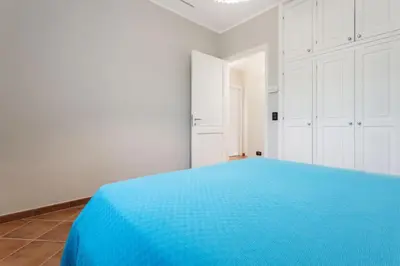 a blue bed in a white room with white cabinets at Villa NìMia in Castellammare del Golfo