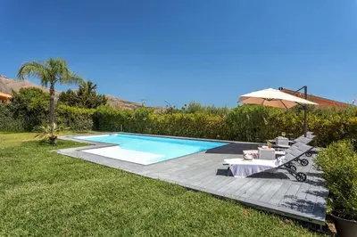 a swimming pool with a table and an umbrella at Villa NìMia in Castellammare del Golfo