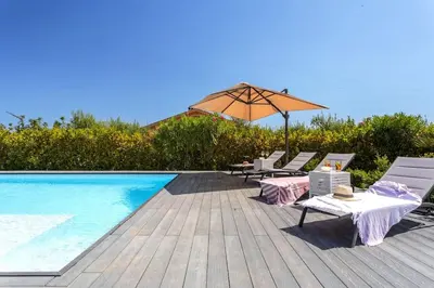 a pool with chairs and an umbrella on a deck at Villa NìMia in Castellammare del Golfo