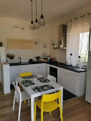 a kitchen with a white table and yellow chairs at Holiday House Nonna Grazia in Trappeto