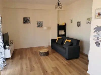 a living room with a black couch and wooden floors at Holiday House Nonna Grazia in Trappeto