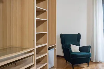 a green chair sitting next to a book shelf at Cavour Elegant apartment At Massimo Theater in Palermo