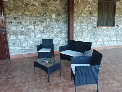 three chairs and a table in front of a stone wall at Fattoria F.lli Marsolo in Chiusa Sclafani