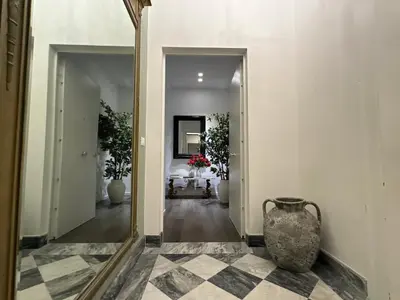 a mirror in a hallway with a vase on the floor at Victoria's Apartment in Palermo
