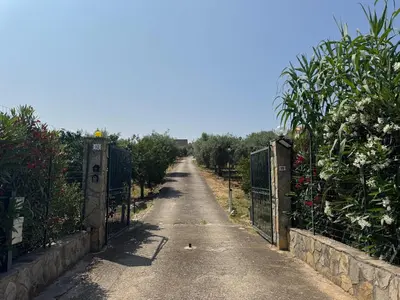 an empty road with a gate and a bird on the road at Le Casette di campagna #2 in Campofelice di Roccella
