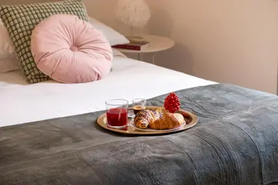 a plate of food on a bed with a drink and strawberries at Ermosa Suite in Palermo