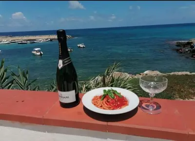 a bottle of wine and a plate of pasta and a glass at LA TERRAZZA SUL MARE monolocale con terrazza vicino aereoporto&mare SICILIAN VINTAGE STYLE BEACH HOUSE in Cinisi