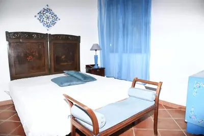a bedroom with a large bed and a chair at Villa Maruzza (Sicilia Bedda) in Carini