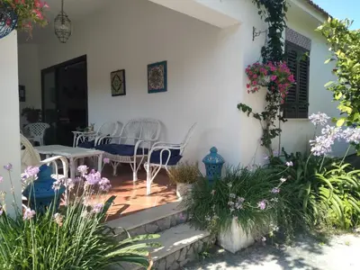 a patio with a table and chairs and flowers at Villa Maruzza (Sicilia Bedda) in Carini