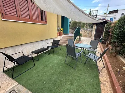 a patio with a table and chairs on the grass at Casa Vacanza Mondello in Palermo