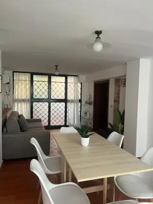 a living room with a wooden table and white chairs at A Due Passi da Mondello in Palermo