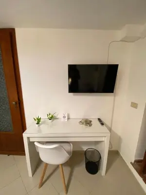 a white desk with a chair and a television on a wall at A Due Passi da Mondello in Palermo
