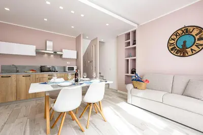 a kitchen and living room with a large clock on the wall at I Tre Golfi - Residenza Cala Azzurra in San Vito lo Capo