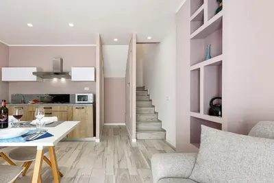 a living room with a table and a stairway at I Tre Golfi - Residenza Cala Azzurra in San Vito lo Capo