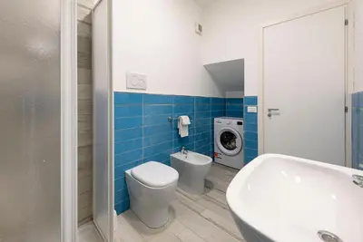 a bathroom with a toilet and a sink and a washing machine at I Tre Golfi - Residenza Cala Azzurra in San Vito lo Capo