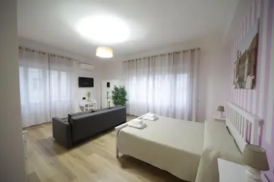 a white bedroom with a bed and a couch at Casa di Paola in Palermo