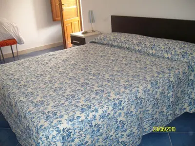 a bedroom with a bed with a blue comforter at casa cocos in San Vito lo Capo