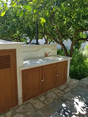 a kitchen with wooden cabinets in front of a tree at casa cocos in San Vito lo Capo