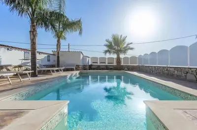 a swimming pool with palm trees and a building at Villa Antonio in Cinisi