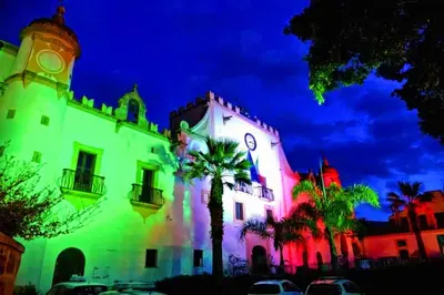 a white building with a clock tower and palm trees at Villa Antonio in Cinisi