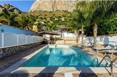 a pool at a hotel with a mountain in the background at Villa Antonio in Cinisi