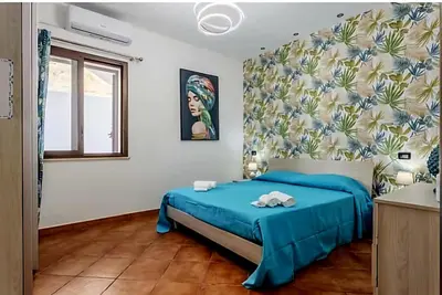 a bedroom with a blue bed in a white room at Villa Antonio in Cinisi