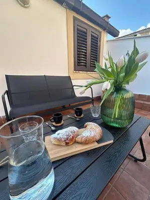 a wooden table with a glass of water and a vase at Kappa's house in Palermo