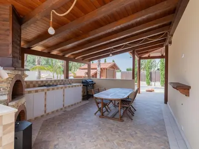 a patio with a table and a kitchen with a fireplace at Villa Kamarà in Castellammare del Golfo