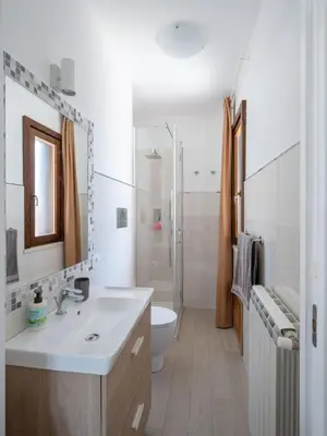 a white bathroom with a sink and a toilet at Villa Kamarà in Castellammare del Golfo