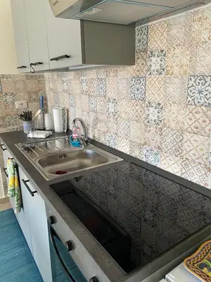 a kitchen with a sink and a tiled wall at La Casa di Gus in Palermo