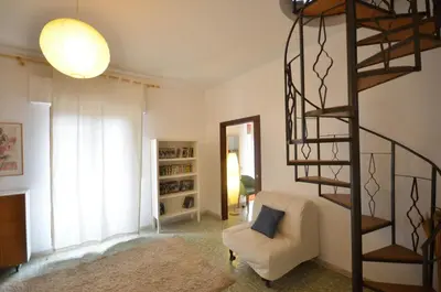 a living room with a spiral staircase and a chair at Casa Garofani in Carini
