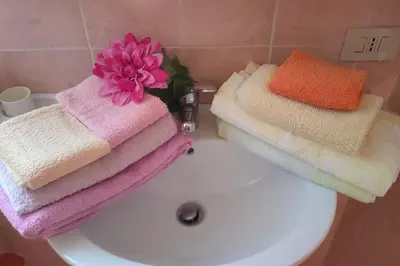 a pile of towels sitting on top of a white sink at Casetta vista mare 2 Climatizzata in Castellammare del Golfo