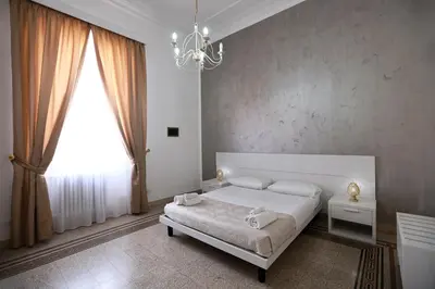 a bedroom with a white bed and a chandelier at Il Siciliano room’s & suite in Palermo