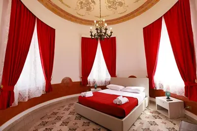 a bedroom with a bed with red curtains and a chandelier at Il Siciliano room’s & suite in Palermo
