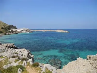 a large body of water with rocks and blue water at Sikanart Home in Palermo