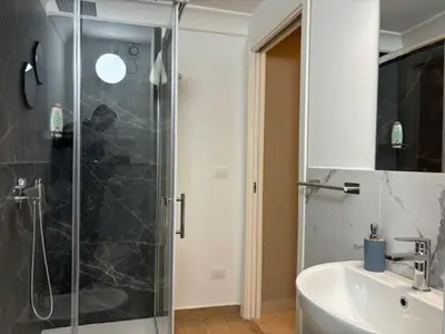 a bathroom with a glass shower and a sink at Sikanart Home in Palermo