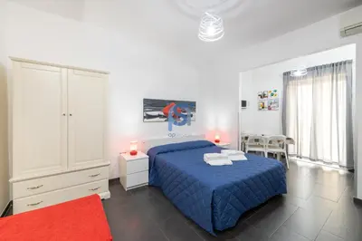a bedroom with a blue bed and a red rug at Il Vittoria - Self Check in in Lascari