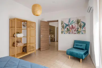 a living room with a blue chair and a bedroom at Palermo of living appartamento Centro Storico in Palermo